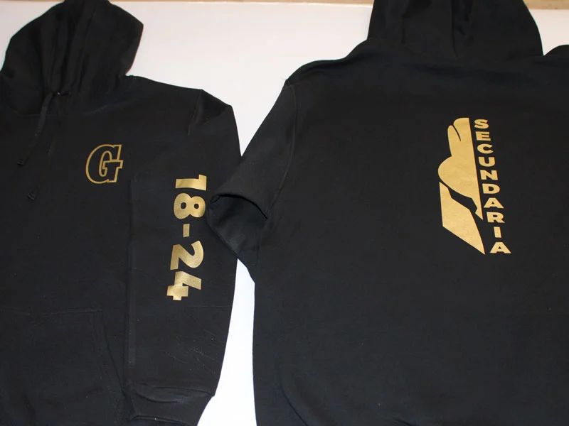 Prendas negras personalizadas con gráficos dorados en el frente y la espalda.